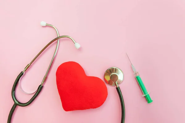 Equipamento de medicina estetoscópio ou seringa de fonendoscópio e coração vermelho isolado no moderno fundo rosa pastel — Fotografia de Stock