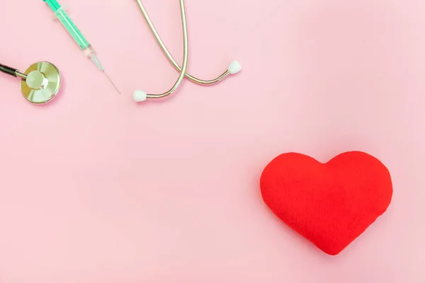 Equipo de medicina estetoscopio o jeringa fonendoscopio y corazón rojo aislado sobre fondo rosa pastel de moda — Foto de Stock