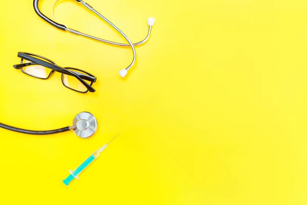 Equipamento médico estetoscópio ou óculos de fonendoscópio e seringa isolados em fundo amarelo moderno — Fotografia de Stock