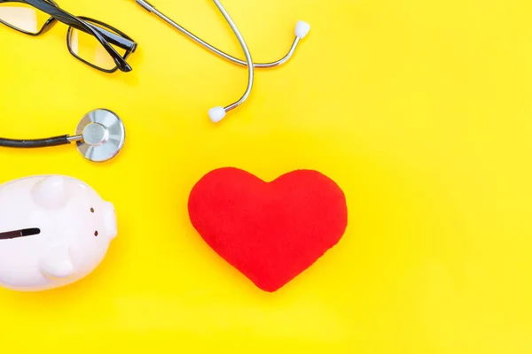 Medicina equipamento médico estetoscópio ou fonendoscópio piggy banco óculos coração vermelho isolado na moda fundo amarelo — Fotografia de Stock