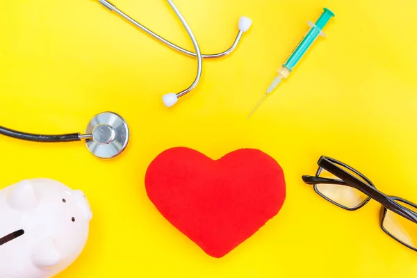Equipamento médico medicina estetoscópio ou fonendoscópio óculos de banco piggy seringa coração vermelho isolado no fundo amarelo da moda — Fotografia de Stock