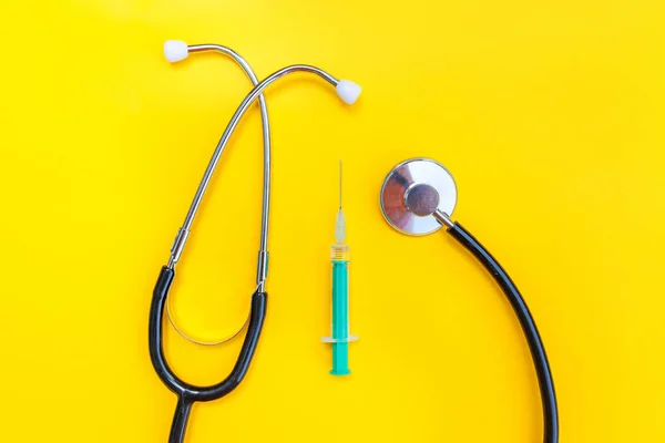 Equipamento de medicina estetoscópio ou fonendoscópio e seringa isolados em fundo amarelo moderno — Fotografia de Stock
