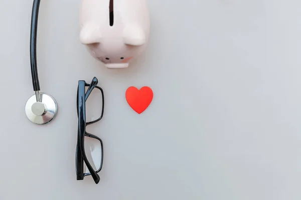 Medicine doctor equipment stethoscope or phonendoscope piggy bank glasses isolated on white background