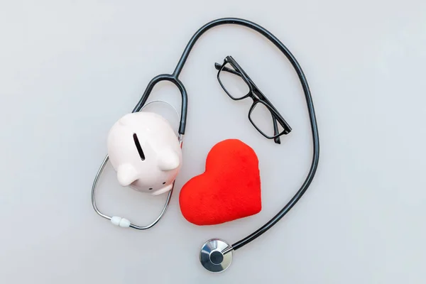 Medicine doctor equipment stethoscope or phonendoscope piggy bank glasses and red heart isolated on white background