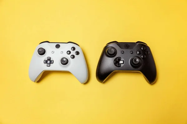 Branco e preto dois joystick no fundo amarelo. Concorrência de jogos de computador conceito de confronto de controle de videogame — Fotografia de Stock