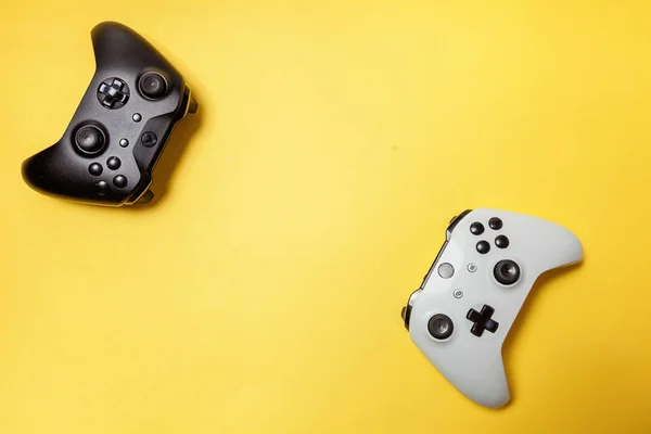 Branco e preto dois joystick no fundo amarelo. Concorrência de jogos de computador conceito de confronto de controle de videogame — Fotografia de Stock