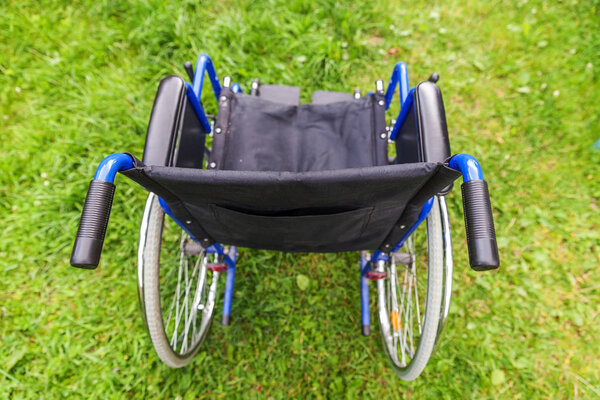 Empty wheelchair standing on grass in hospital park waiting for patient services