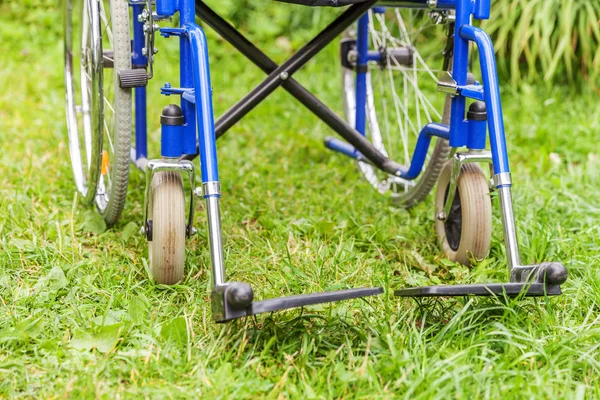 Cadeira de rodas vazia em pé na grama no parque hospitalar esperando pelos serviços do paciente — Fotografia de Stock