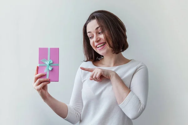 Jeune femme positive tenant petite boîte cadeau rose isolé sur fond blanc. Préparation pour les vacances. Fille regardant heureux et excité — Photo