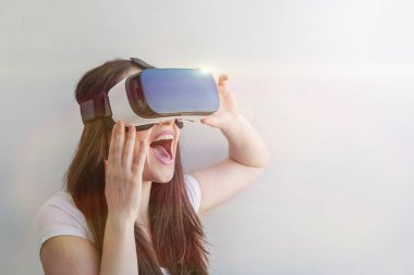 Beyaz arka plan üzerinde sanal gerçeklik Vr gözlük kask kulaklık kullanarak giyen gülümseme genç kadın