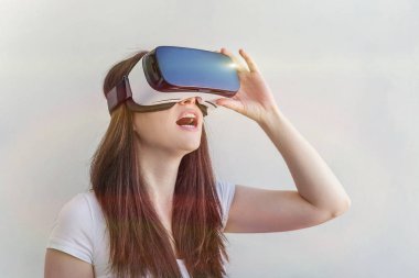 Beyaz arka plan üzerinde sanal gerçeklik Vr gözlük kask kulaklık kullanarak giyen gülümseme genç kadın