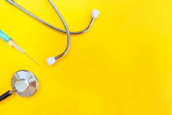 Equipamento de medicina estetoscópio ou fonendoscópio e seringa isolados em fundo amarelo moderno — Fotografia de Stock