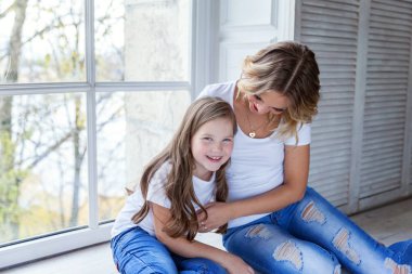 Mutlu aile kadın anne ve küçük kız windiow yakın yatak odasında sarılma oynarken dinlenmek