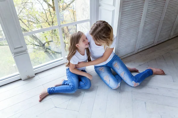 Feliz familia mujer madre y niña pequeña relajarse jugando abrazos en el dormitorio cerca de windiow —  Fotos de Stock