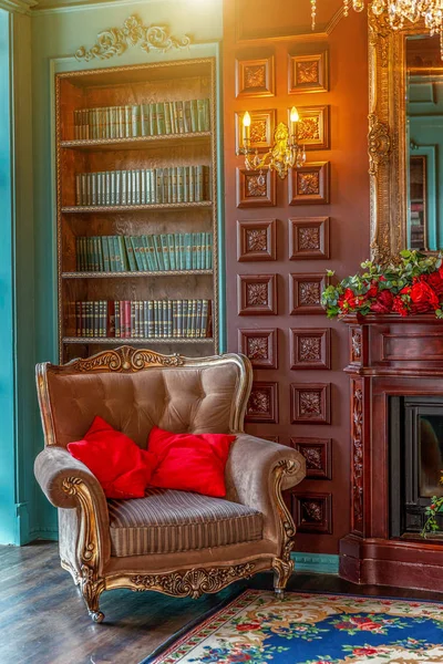 Розкішний класичний інтер'єр домашньої бібліотеки. Вітальня з книжковою полицею, книгами, кріслом для рук, диваном і каміном — стокове фото