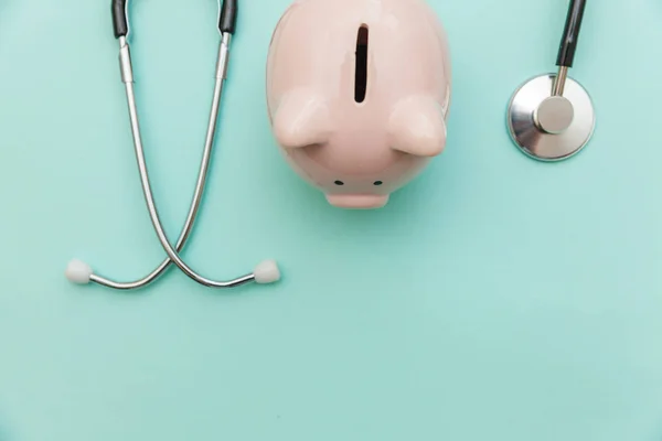 Equipamento médico medicina estetoscópio ou fonendoscópio e porquinho banco isolado no moderno fundo azul pastel — Fotografia de Stock