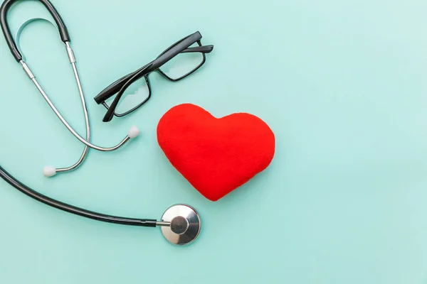 Medicine equipment stethoscope or phonendoscope glasses and red heart isolated on trendy pastel blue background. Instrument device for doctor. Health care life insurance concept — Stock Photo, Image