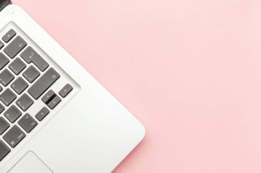 Pembe pastel masa arka planda izole klavye dizüstü bilgisayar. Modern bilgi teknolojisi ve yazılım gelişmeleri
