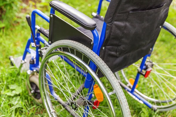 Cadeira de rodas vazia em pé na grama no parque hospitalar esperando pelos serviços do paciente — Fotografia de Stock