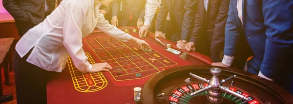 Grupp människor bakom Roulette spelbord i lyx Casino banner — Stockfoto