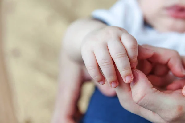 Tiny newborn infant male or female baby hand holding mother finger