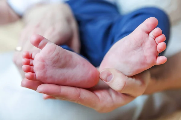 Tiny newborn infant male or female baby feet and toes on mother hand