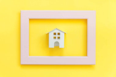 Sadece renkli trendy sarı arka plan izole pembe çerçeve minyatür beyaz oyuncak ev ile tasarım