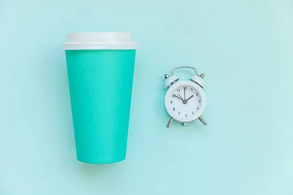 Jednoduše plochý design modrý papír šálek kávy a budík izolovaný na modré pastelové barevné pozadí — Stock fotografie