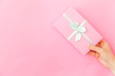 Sadece pembe pastel renkli trendy arka plan izole pembe hediye kutusu tutan kadın kadın el tasarımı