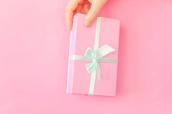 Simply design female woman hand holding pink gift box isolated on pink pastel colorful trendy background — Stock Photo, Image