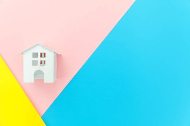 Mavi sarı pembe pastel renkli trendy geometrik arka planda izole minyatür beyaz oyuncak ev