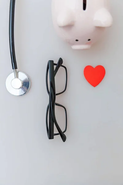 Equipamento médico medicina estetoscópio ou fonendoscópio óculos de banco piggy isolado em fundo branco — Fotografia de Stock