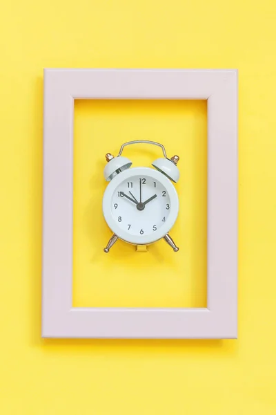 Ringing twin bell vintage alarm clock in pink frame isolated on yellow colorful trendy background — Stock Photo, Image