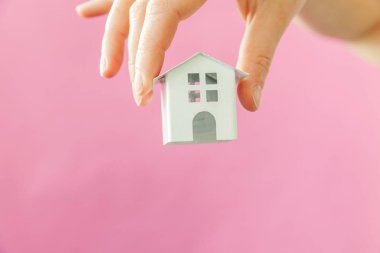 Sadece pembe pastel renkli trendy arka plan izole minyatür beyaz oyuncak ev tutan kadın kadın el tasarımı