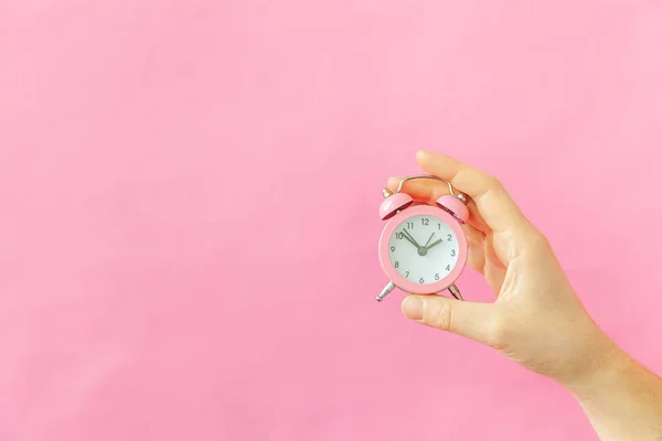 Simply design female woman hand holding ringing twin bell alarm clock isolated on pink pastel colorful trendy background — Stock Photo, Image