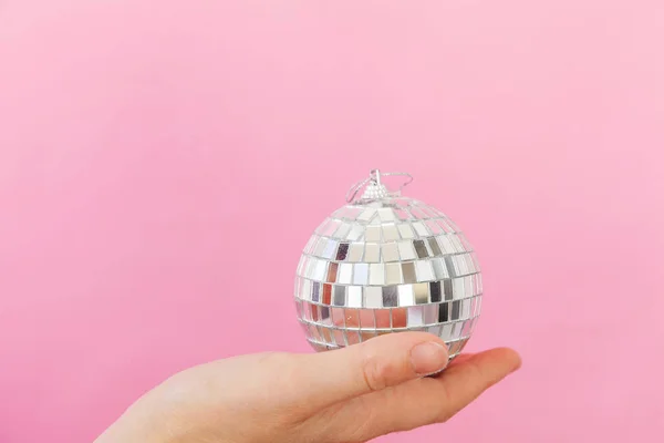 Просто минимальный дизайн женская рука держа Рождественский орнамент мяч изолирован на розовый пастель красочный модный фон — стоковое фото