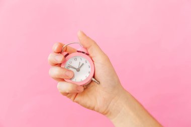 Sadece tasarım kadın kadın el tutan zil ikiz çan çalar saat pembe pastel renkli trendy arka plan izole