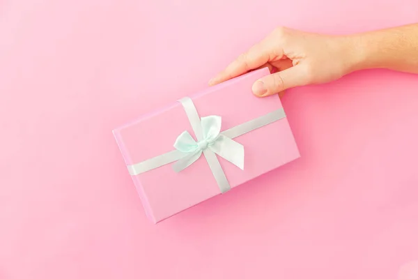 Simply design female woman hand holding pink gift box isolated on pink pastel colorful trendy background — Stock Photo, Image