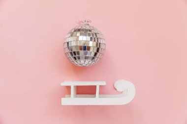 Basit bir kompozisyon kış nesneleri süs topu kızağı pembe pastel arka planda izole