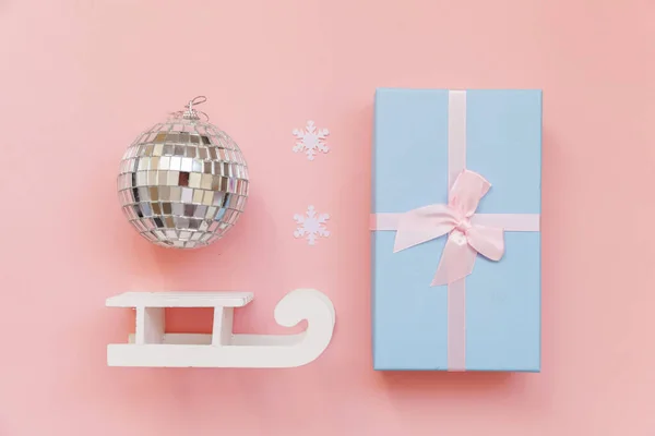 Просто минимальная композиция зимних объектов украшения мяч сани подарочная коробка изолированы на розовом пастельном модном фоне — стоковое фото