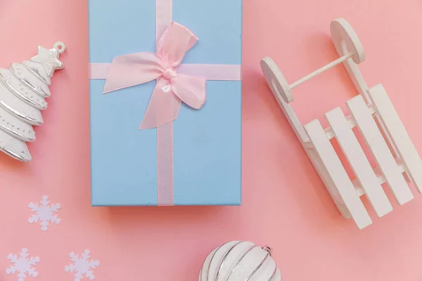 Simplesmente composição mínima objetos de inverno ornamento bola abeto árvore trenó caixa de presente isolado no fundo da moda pastel rosa — Fotografia de Stock