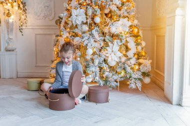 Evde Noel ağacının yanında hediye kutusu olan küçük kız.
