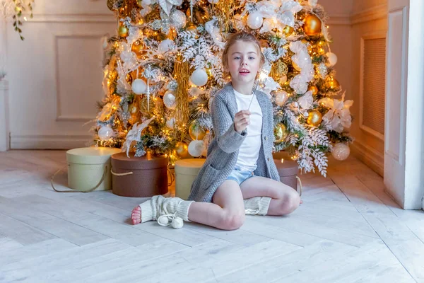 Little girl with sparkler near Christmas tree at home — ストック写真