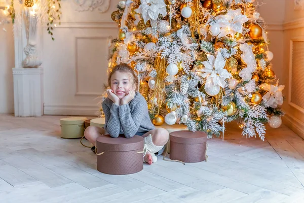 Маленькая девочка с подарочной коробкой возле елки дома — стоковое фото