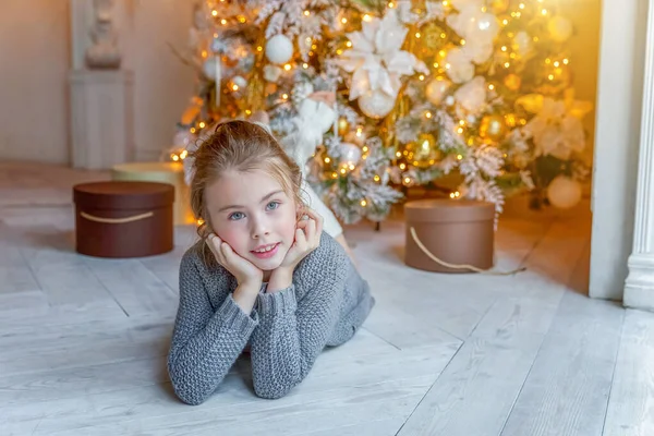 Menina com caixa de presente perto da árvore de Natal em casa — Fotografia de Stock