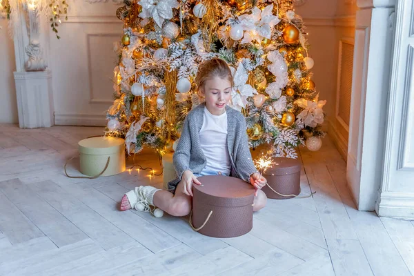 Little girl with sparkler near Christmas tree at home — ストック写真