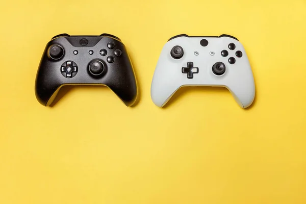 黄色の背景に白と黒の2つのジョイスティック。コンピュータゲーム競技大会ビデオゲーム制御対決コンセプト — ストック写真