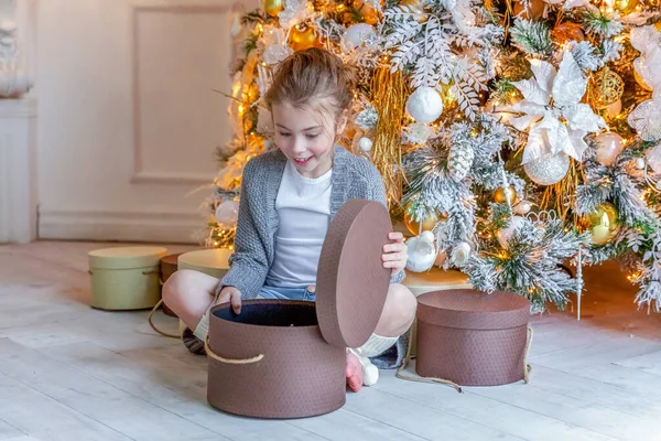 Маленькая девочка с подарочной коробкой возле елки дома — стоковое фото