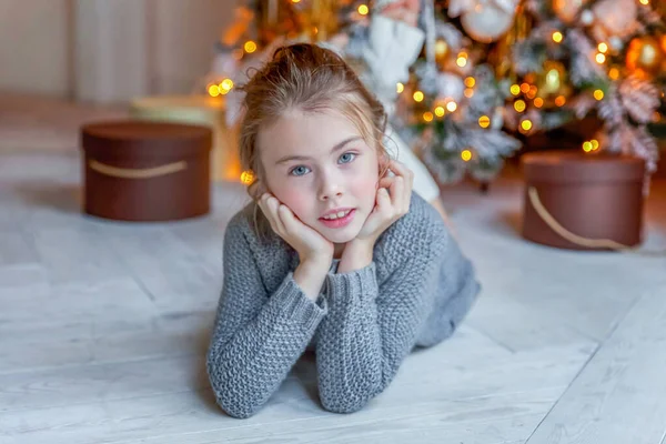 Menina com caixa de presente perto da árvore de Natal em casa — Fotografia de Stock