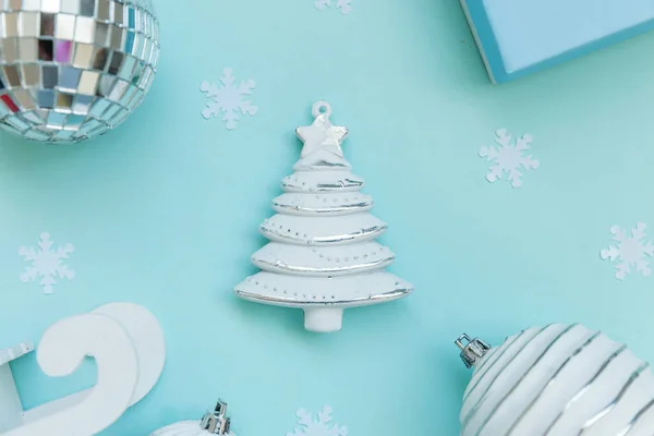 Simplesmente composição mínima objetos de inverno ornamento trenó abeto árvore bola caixa de presente isolado no fundo da moda pastel azul — Fotografia de Stock